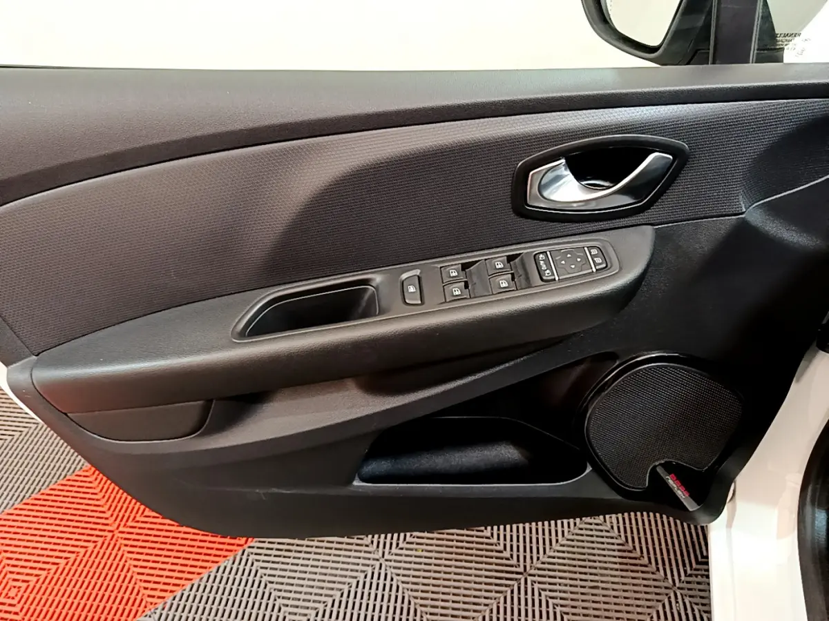 Gros plan sur la porte avant gauche noire de la Renault Clio blanche, avec commandes électriques et haut-parleur intégré.