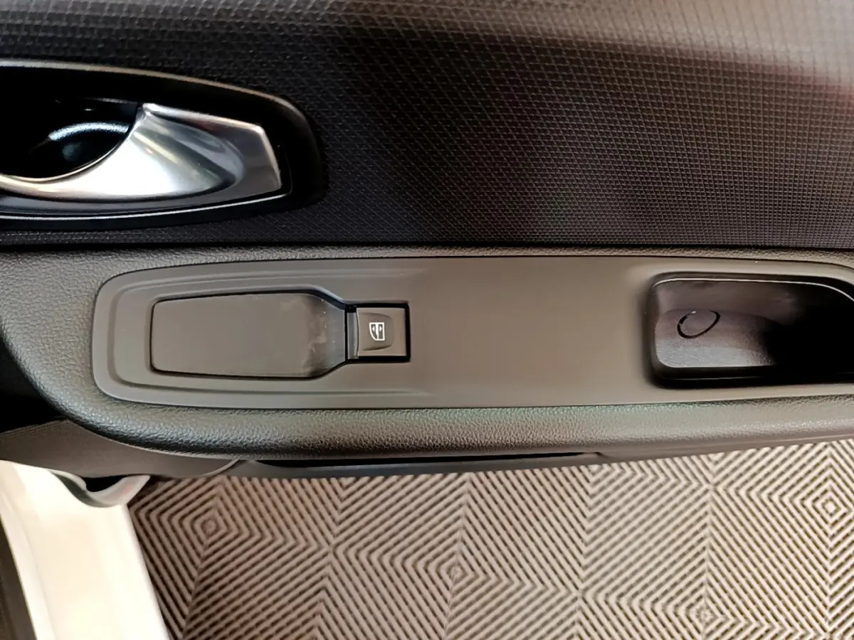 Gros plan sur la poignée intérieure et le bouton de lève-vitre côté conducteur d'une Renault Clio blanche 2019.