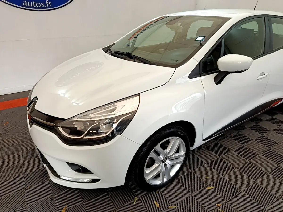 Renault Clio Business TCe 90 blanche vue en 3/4 avant droit, avec phares LED et jantes alliage visibles.