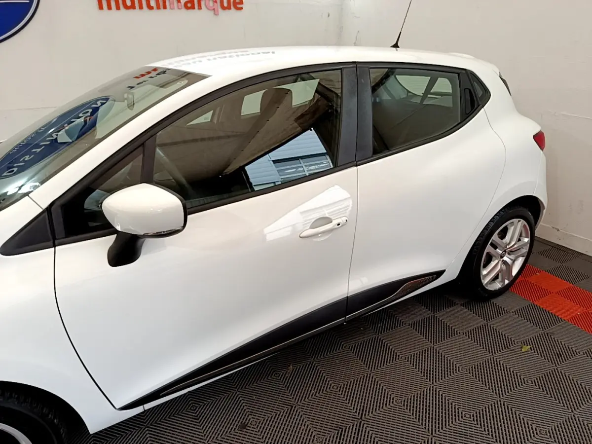Profil côté gauche d'une Renault Clio Business TCe 90 blanche, avec rétroviseur et poignées assortis visibles.