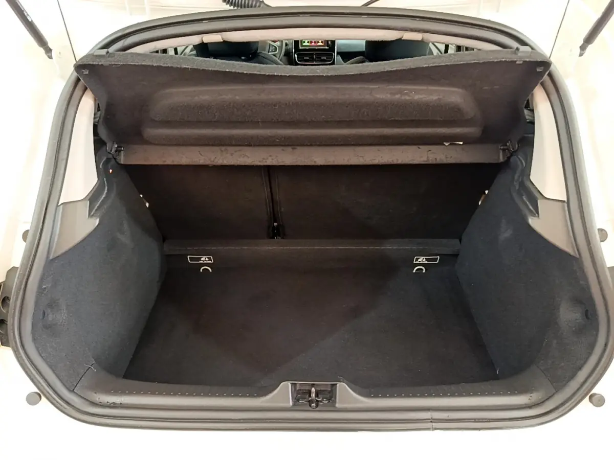 Coffre ouvert d'une Renault Clio Business blanche, vue de l'arrière montrant l'espace de chargement vide et la tablette arrière.