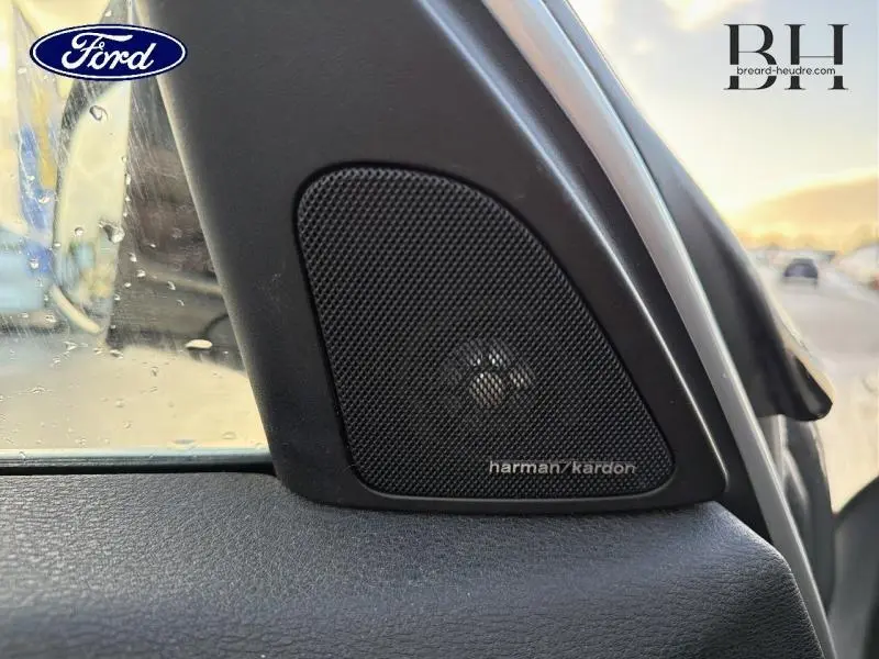 Gros plan sur le haut-parleur Harman Kardon côté gauche dans l'habitacle d'une BMW X1 Mineralgrau de 2014.