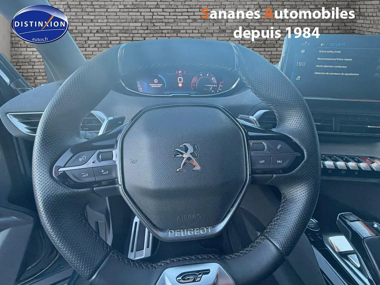 Vue rapprochée du volant cuir perforé Peugeot 3008 GT 2023 avec commandes intégrées et tableau de bord numérique.