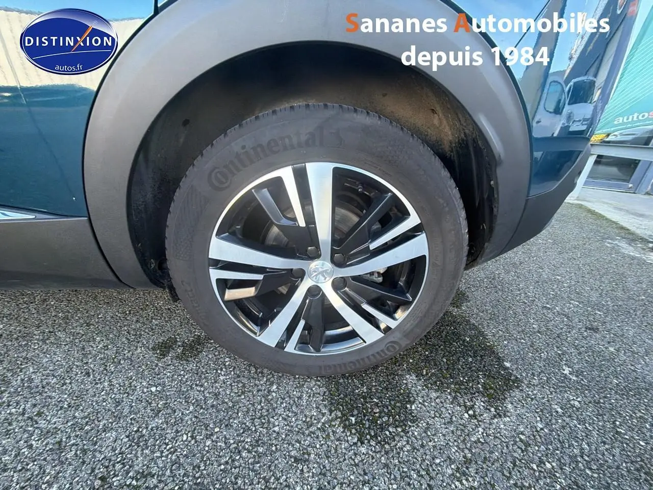Gros plan sur la roue avant droite avec jante alliage bicolore du Peugeot 3008 bleu métallisé.