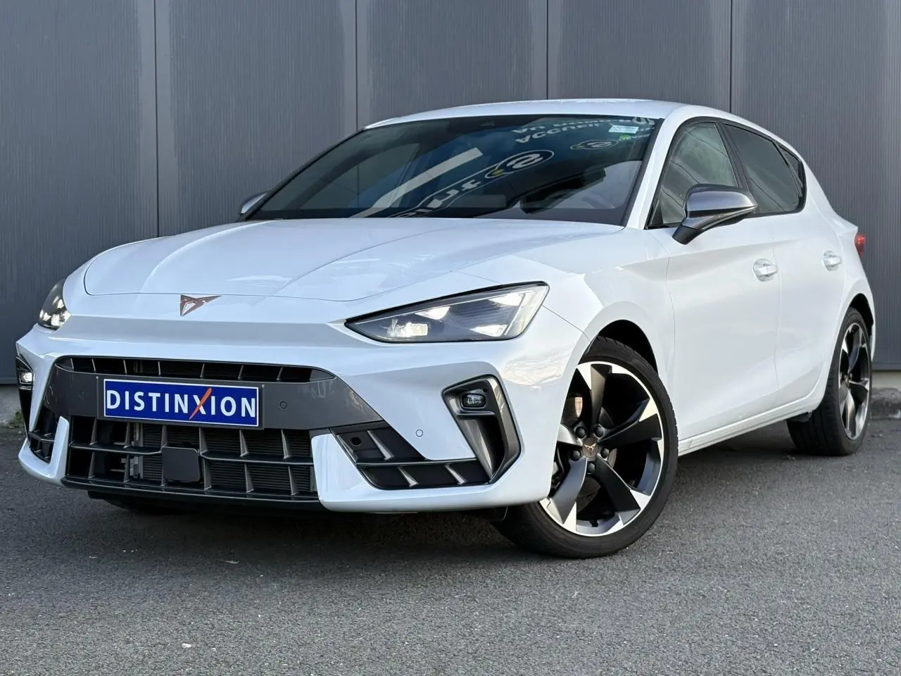 Vue 3/4 avant droite d'une CUPRA Leon blanche Neige avec jantes alliage noires et logo CUPRA sur la calandre.