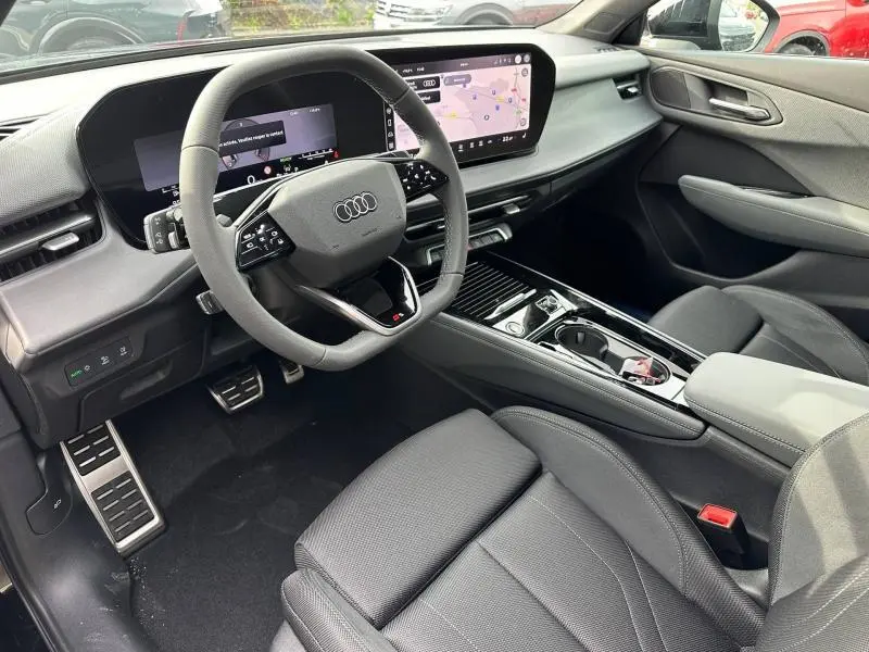 Intérieur noir de l'Audi Q3 2026 vu côté conducteur, avec volant multifonction et écran tactile large.