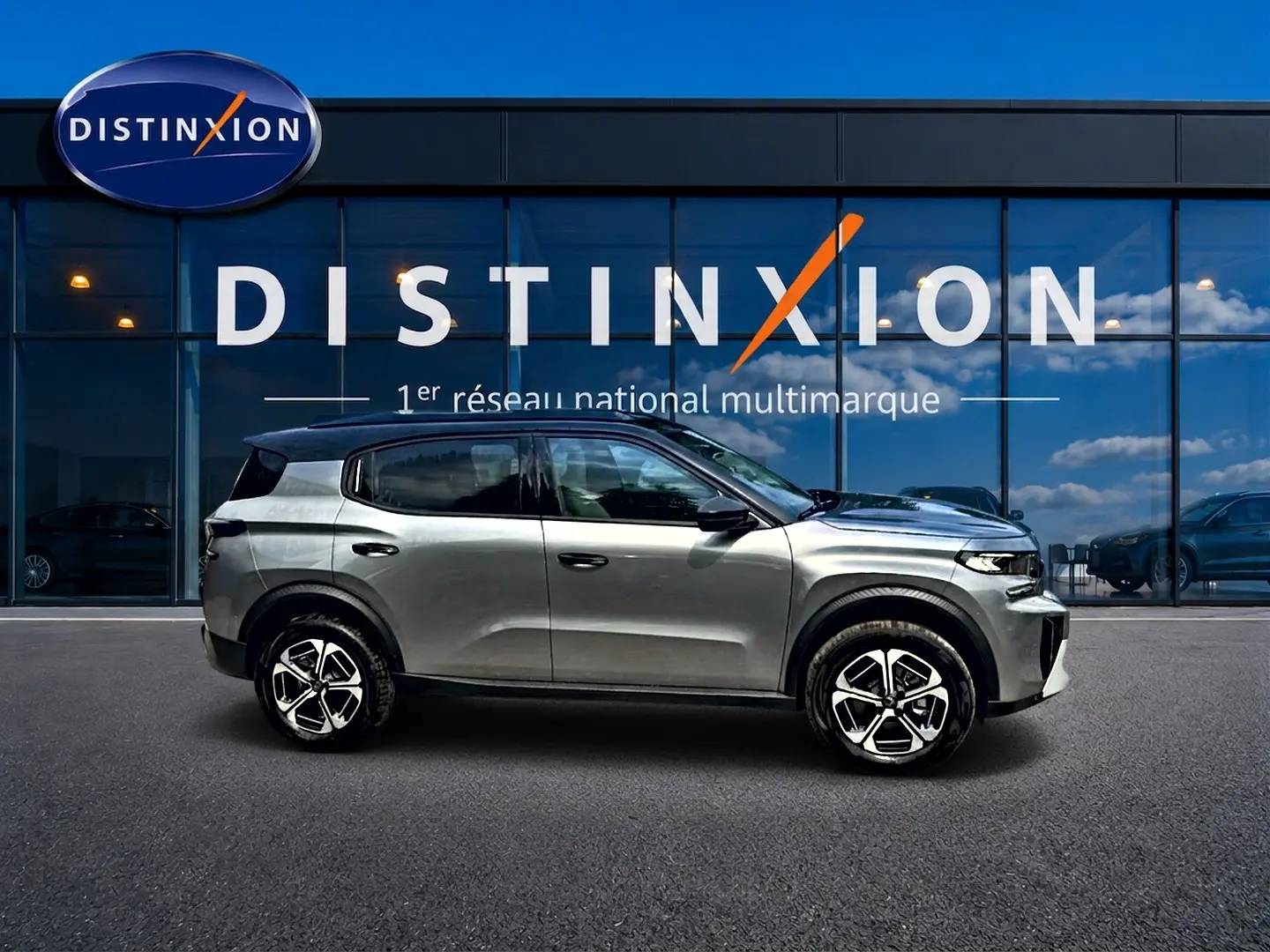 Profil côté gauche du Citroën C3 Aircross gris mercury 2026, avec jantes alu et toit noir visible devant une vitrine Distinxion.