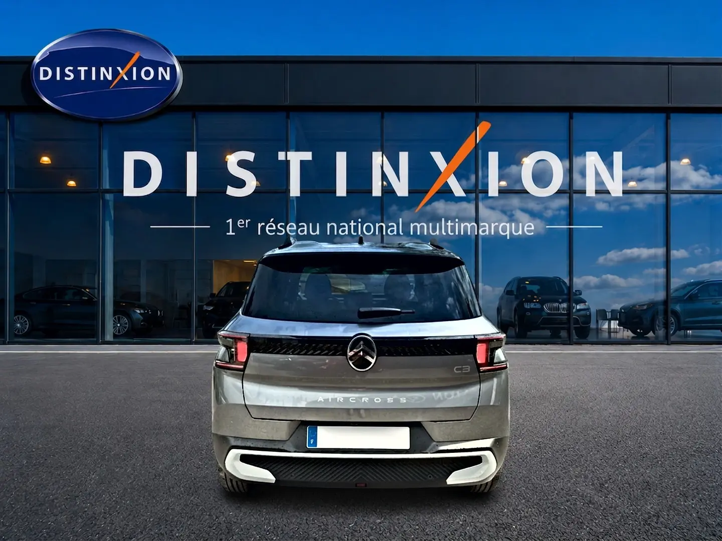 Vue arrière du Citroën C3 Aircross gris mercury 2026, avec feux LED et logo centré sur un parking devant un showroom.