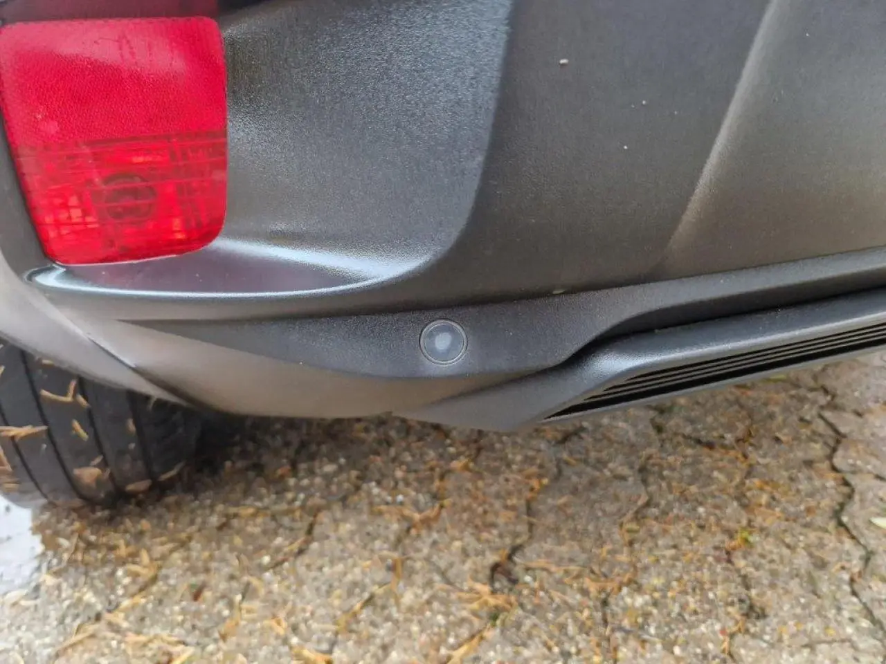 Gros plan sur le pare-chocs arrière noir du Peugeot 3008 2019 avec feu rouge et capteur de stationnement visible.