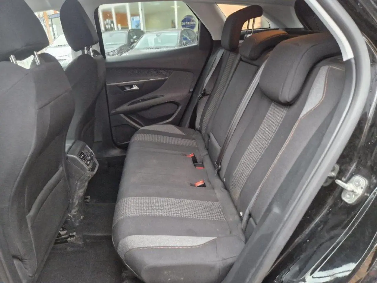 Vue côté droit de l'intérieur arrière d'une Peugeot 3008 noire, montrant les sièges tissu et les aérateurs arrière.