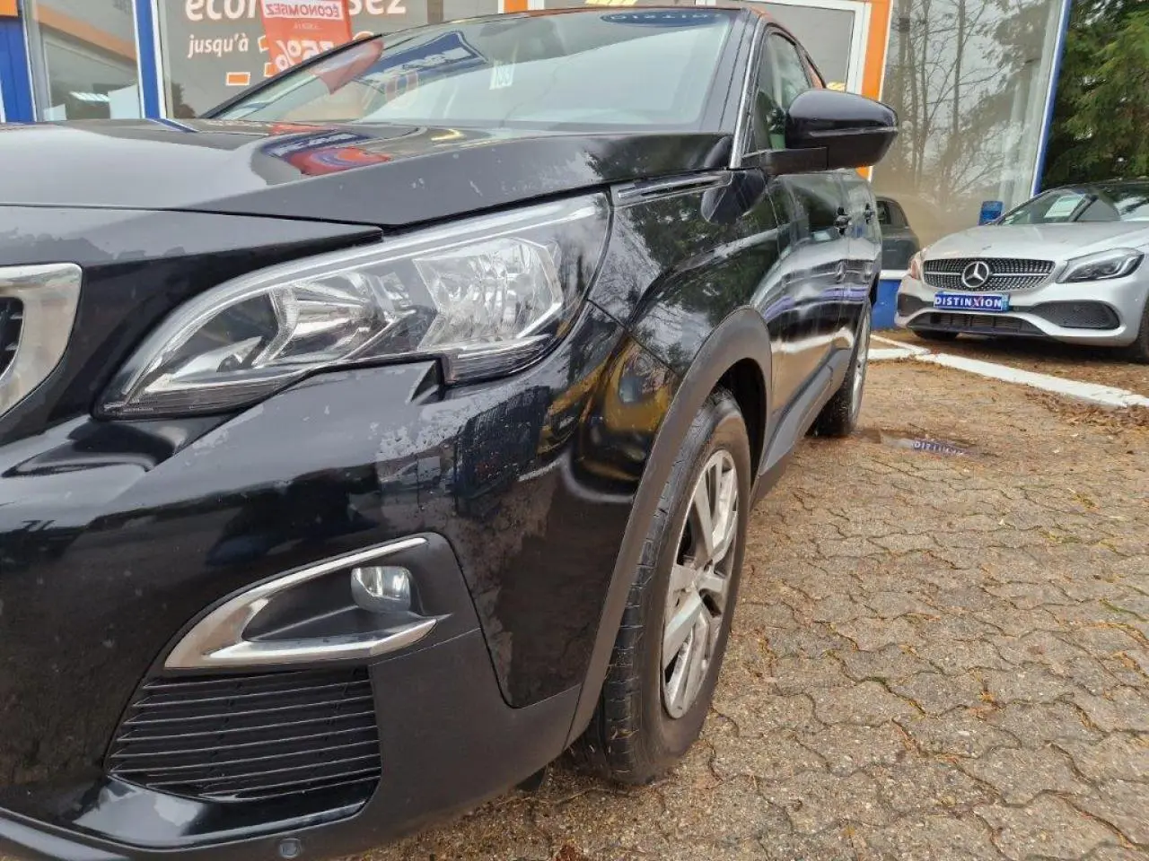 Vue 3/4 avant gauche d'un Peugeot 3008 noir brillant avec jantes alliage et phares LED visibles.