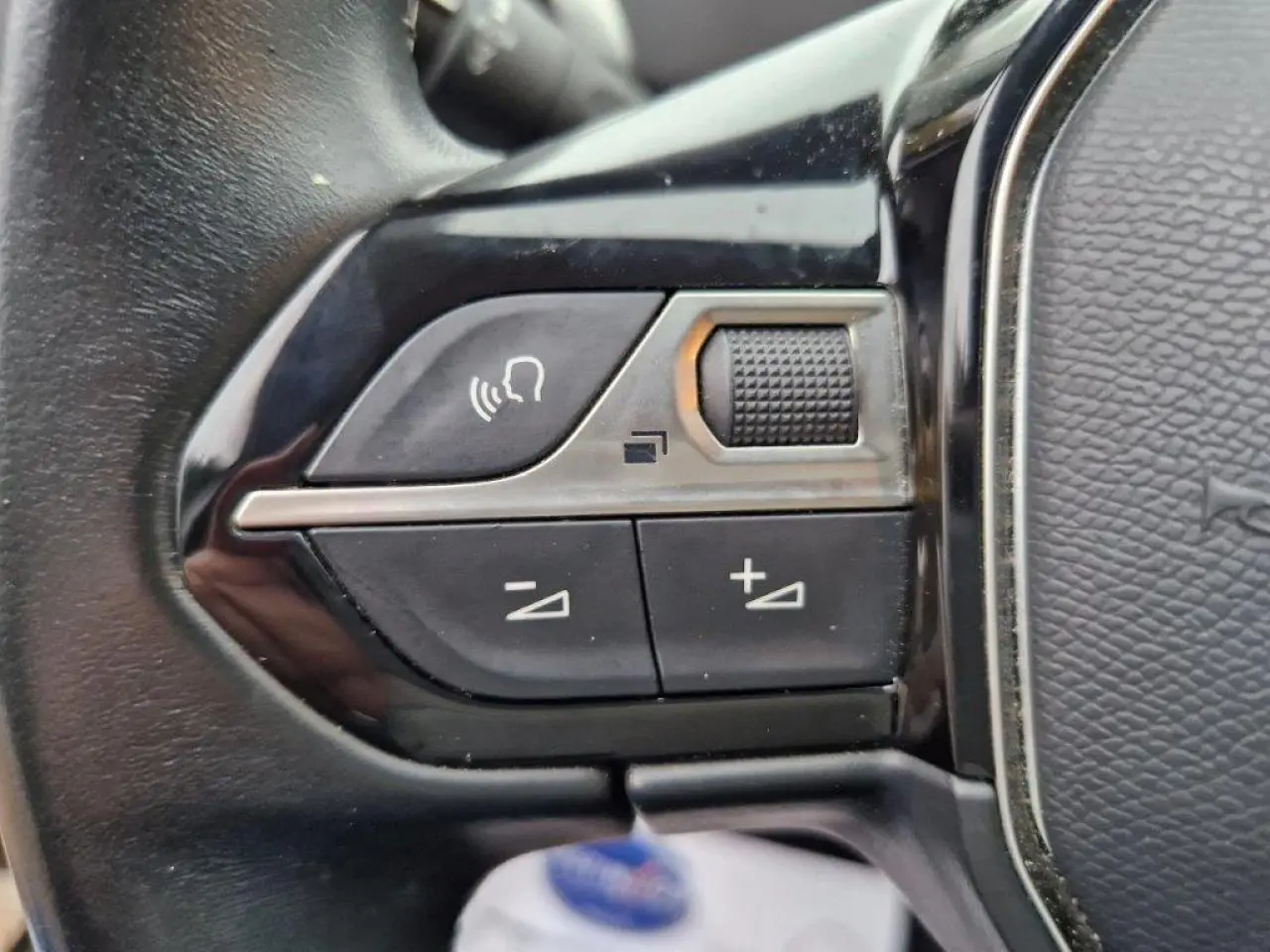 Gros plan sur les commandes vocales et volume du volant cuir noir du Peugeot 3008 noir 2019 côté gauche.