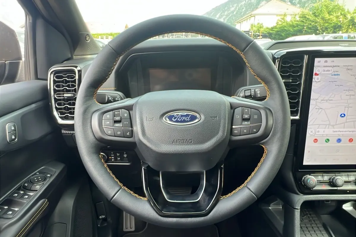 Volant en cuir noir avec surpiqûres marron du Ford Ranger 2.3 PHEV Wildtrak Plus 2025, vue de face sur le tableau de bord et écran tactile.