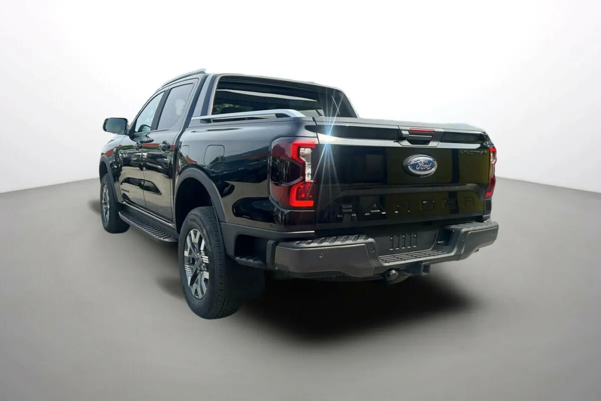 Vue 3/4 arrière du Ford Ranger 2025 noir agate, mettant en valeur la benne et les feux arrière distinctifs Wildtrak Plus.
