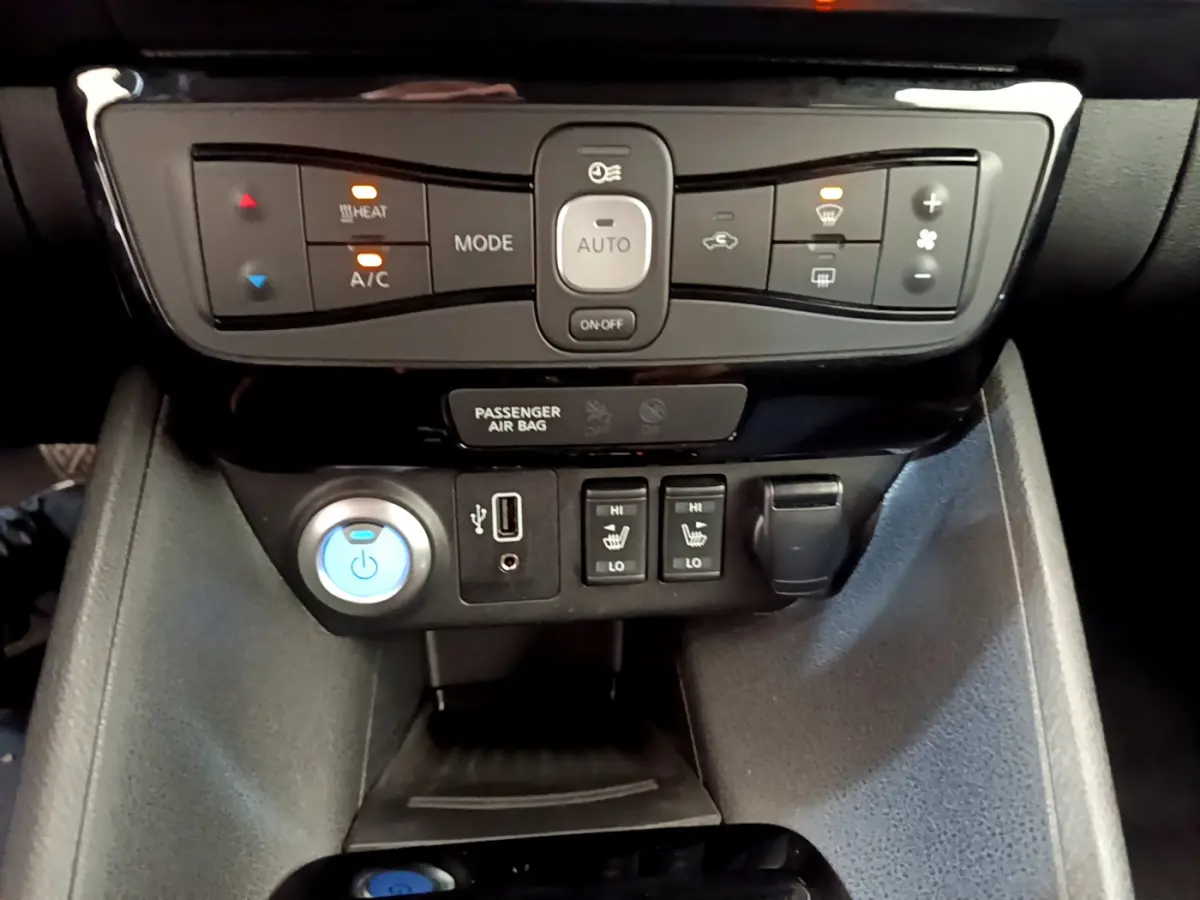 Vue rapprochée du tableau de bord central de la Nissan Leaf 62 kWh blanc, montrant commandes climatisation et sièges chauffants.