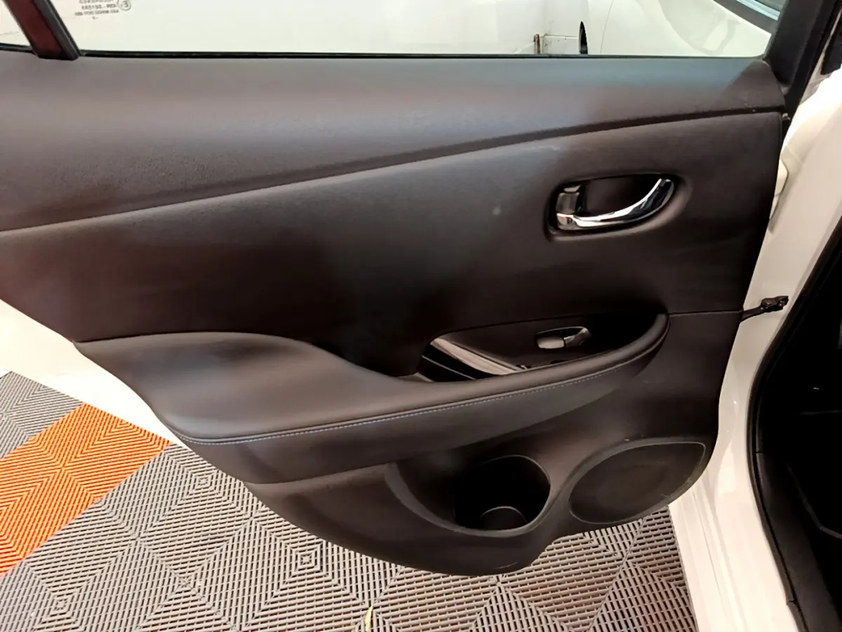 Gros plan sur la porte intérieure côté gauche blanche du Nissan LEAF 62 kWh Business+ avec accoudoir et poignée chrome.