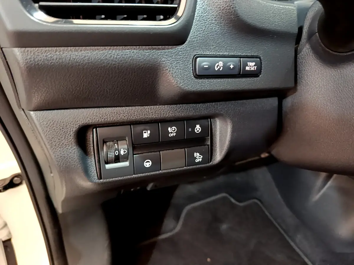 Gros plan sur les commandes de réglage et d'assistance côté conducteur du tableau de bord noir du Nissan Leaf blanc 2020.