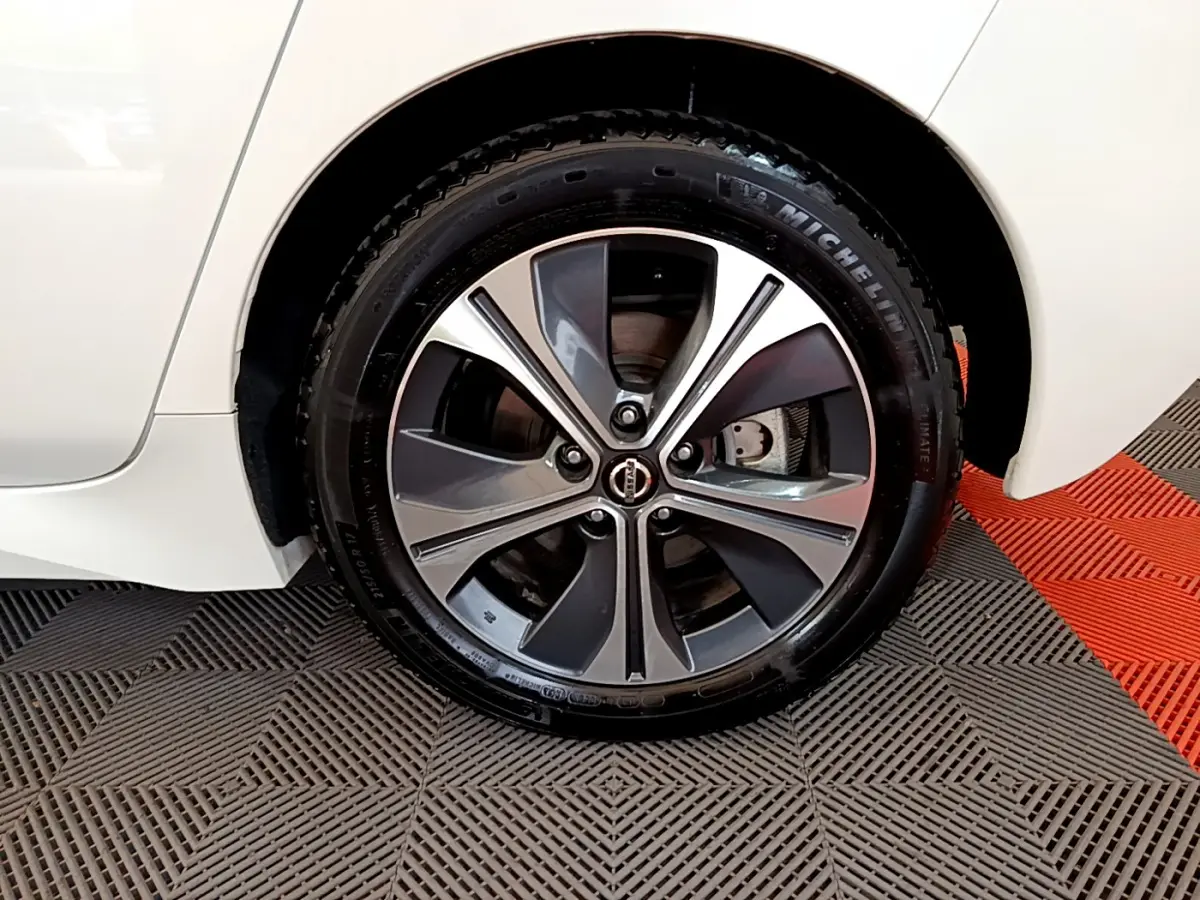 Gros plan sur la roue avant droite avec jante alliage bicolore d'une Nissan Leaf blanche 2020 électrique.