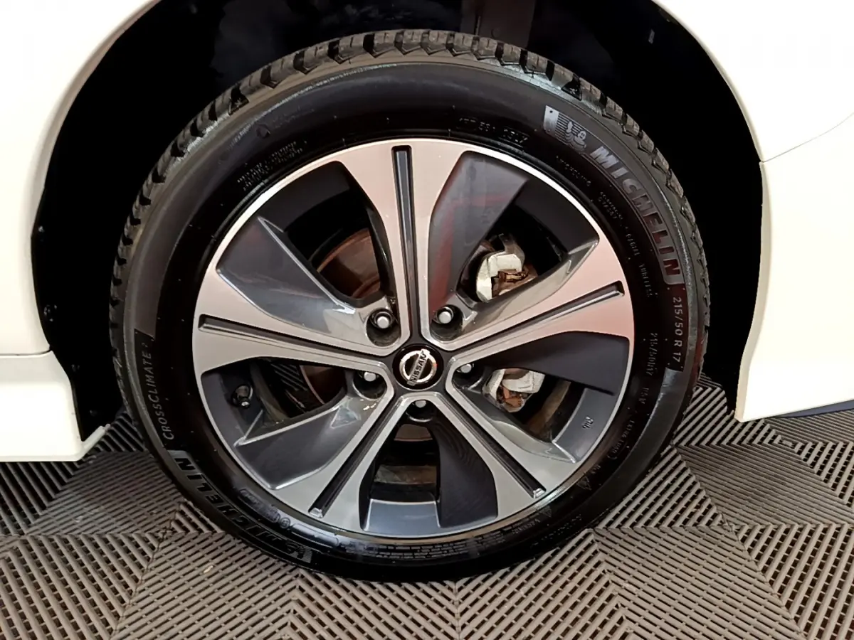 Gros plan sur la jante alliage bicolore et pneu Michelin d'une Nissan Leaf blanche côté avant droit.