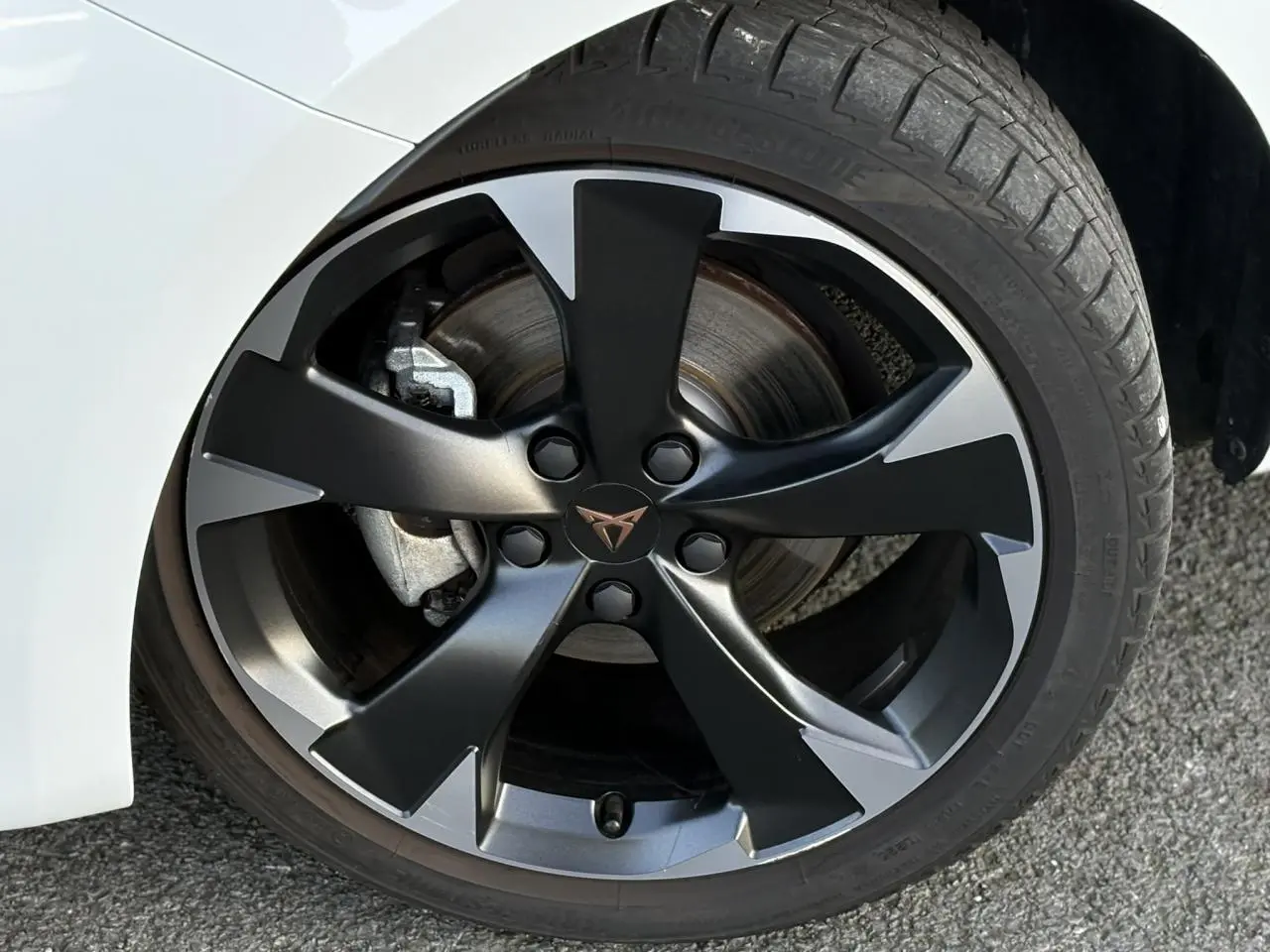 Gros plan sur la jante alliage 18'' bicolore noir et gris du côté avant droit d'une CUPRA Leon Blanc Neige.