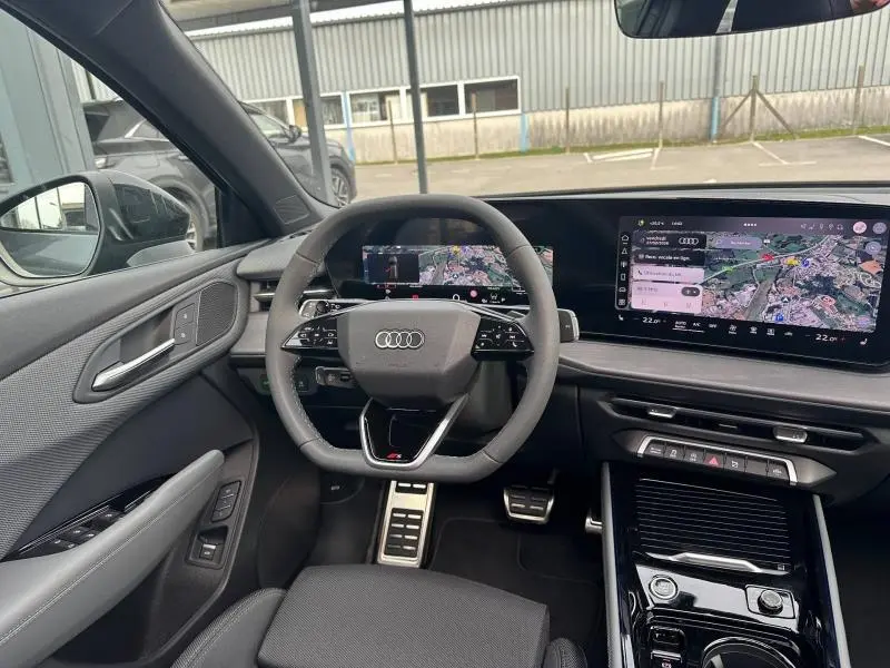 Vue intérieure de l'Audi Q3 2026 gris, montrant le volant S line, le tableau de bord numérique et l'écran tactile large.