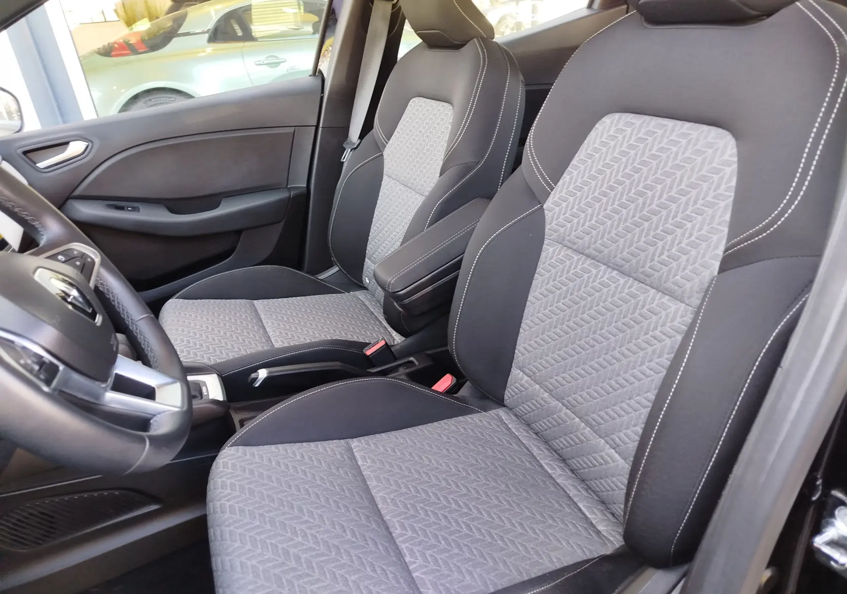 Vue intérieure côté conducteur de la Renault Clio 1.6 E-Tech 140ch Limited 2022 avec sièges tissu bicolore gris et noir.