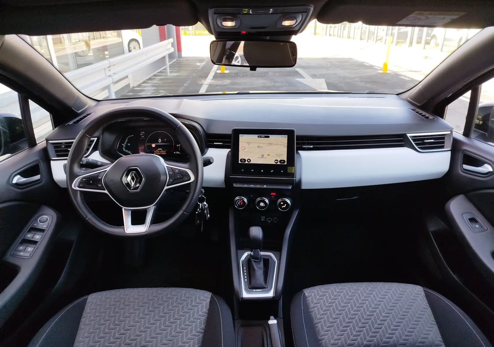 Vue intérieure avant de la Renault Clio 1.6 E-Tech 140ch Limited 2022, tableau de bord noir et blanc avec écran tactile central.