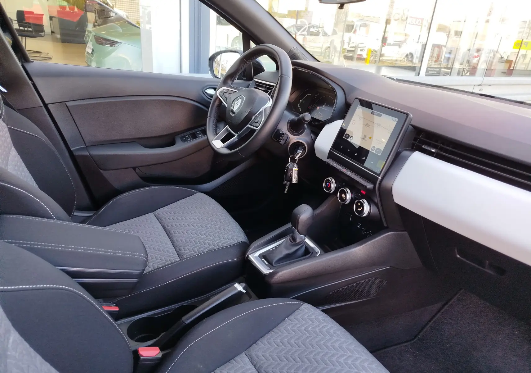 Vue intérieure côté conducteur de la Renault Clio 1.6 E-Tech 2022 avec tableau de bord noir et écran tactile central.