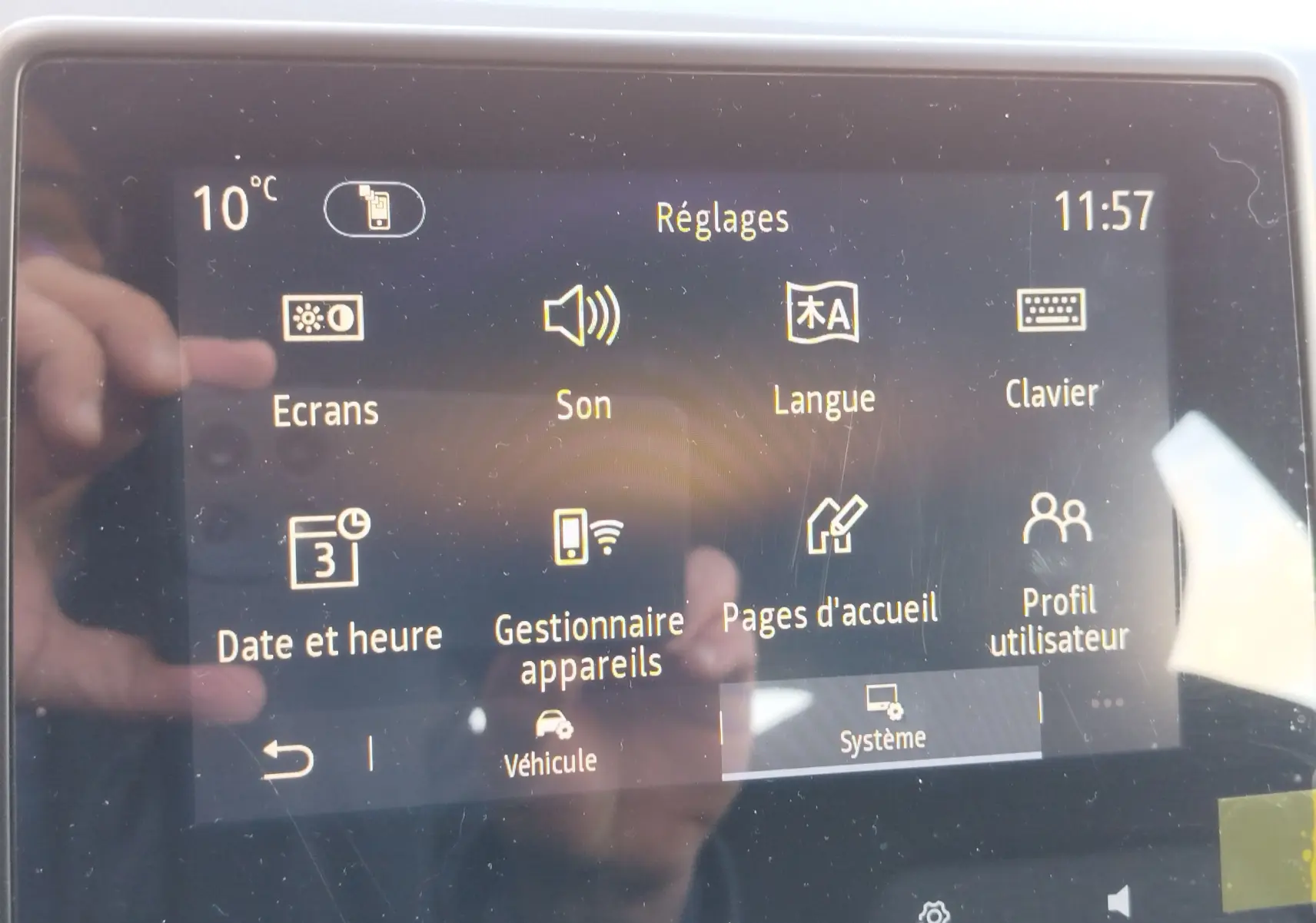 Écran tactile central de la Renault Clio 1.6 E-Tech 140ch Limited 2022 affichant le menu Réglages à 11h57, avec reflet de main visible.