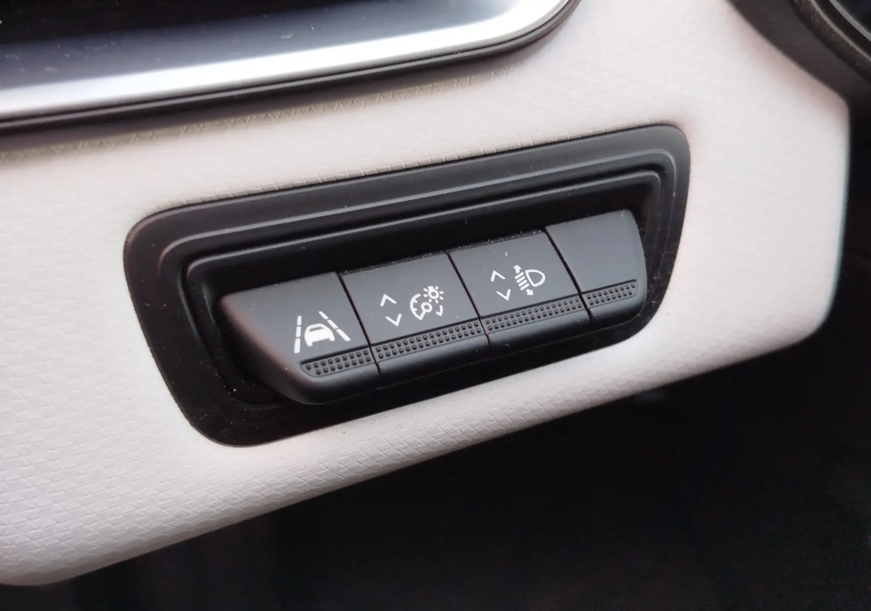 Gros plan sur les boutons de réglage noirs du tableau de bord blanc cassé de la Renault Clio 1.6 E-Tech noir étoile.