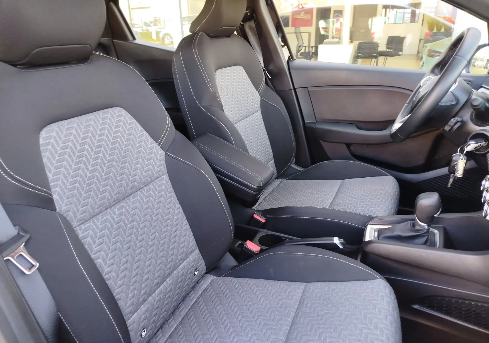 Vue intérieure côté droit de la Renault Clio 1.6 E-Tech 2022, sièges tissu gris à motifs et volant noir visible.