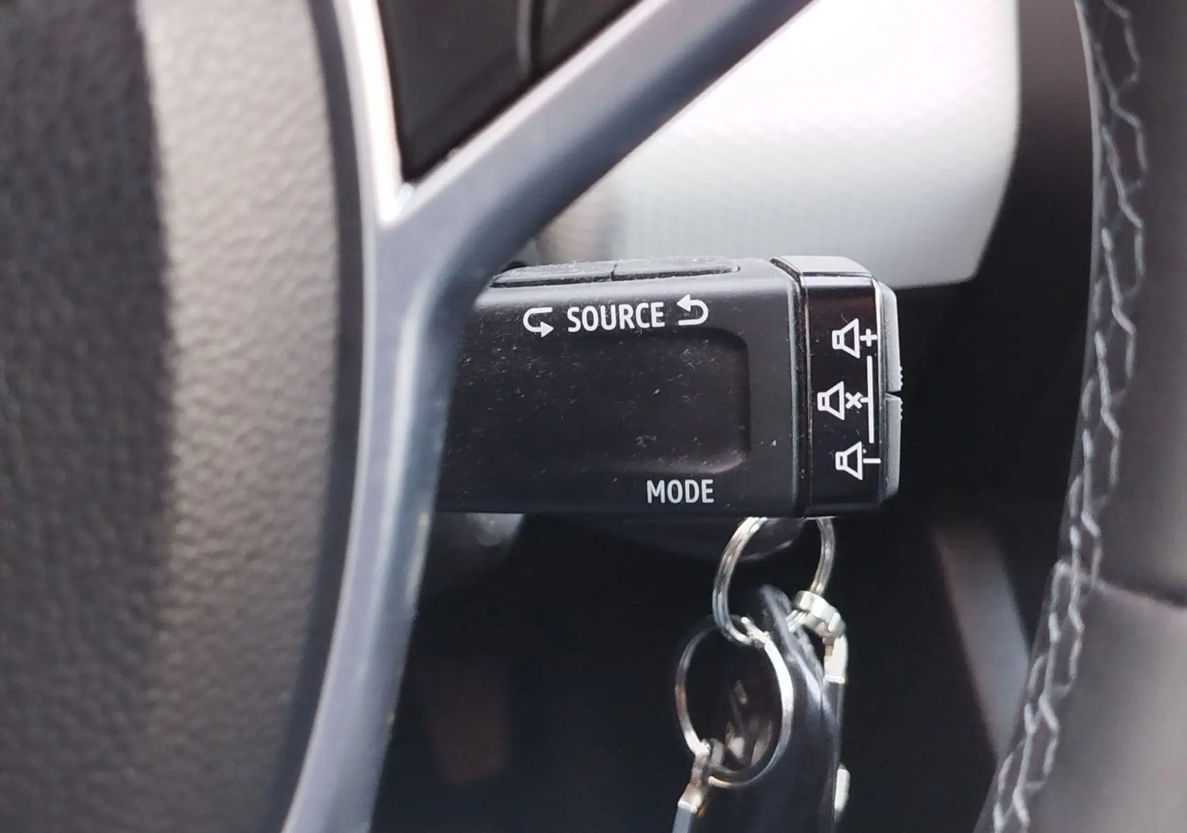 Gros plan sur la commande au volant noir de la Renault Clio 1.6 E-Tech 2022 avec clés accrochées, bouton Source et Mode visibles.