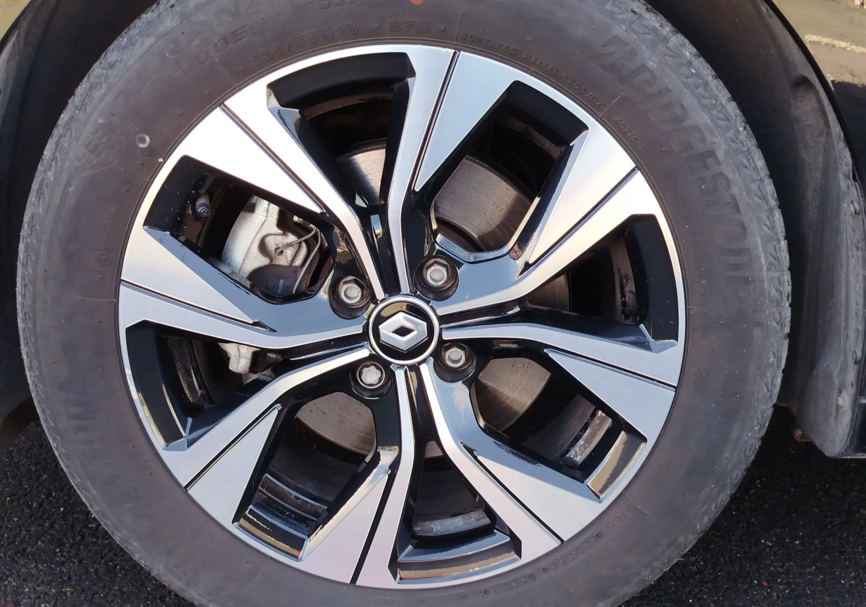 Gros plan sur la jante alliage bicolore noire et argentée avec logo Renault au centre, montée sur pneu Bridgestone.