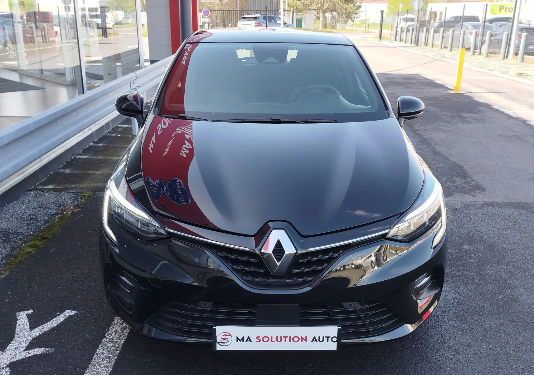 Vue avant d'une Renault Clio 1.6 E-Tech 140ch Limited 2022 en noir étoile, avec phares LED allumés et calandre chromée.