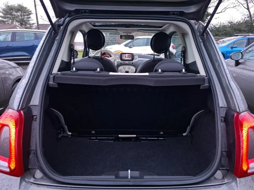 Coffre ouvert vu de l'arrière d'une Fiat 500 gris Electroclash, intérieur noir avec tableau de bord visible.