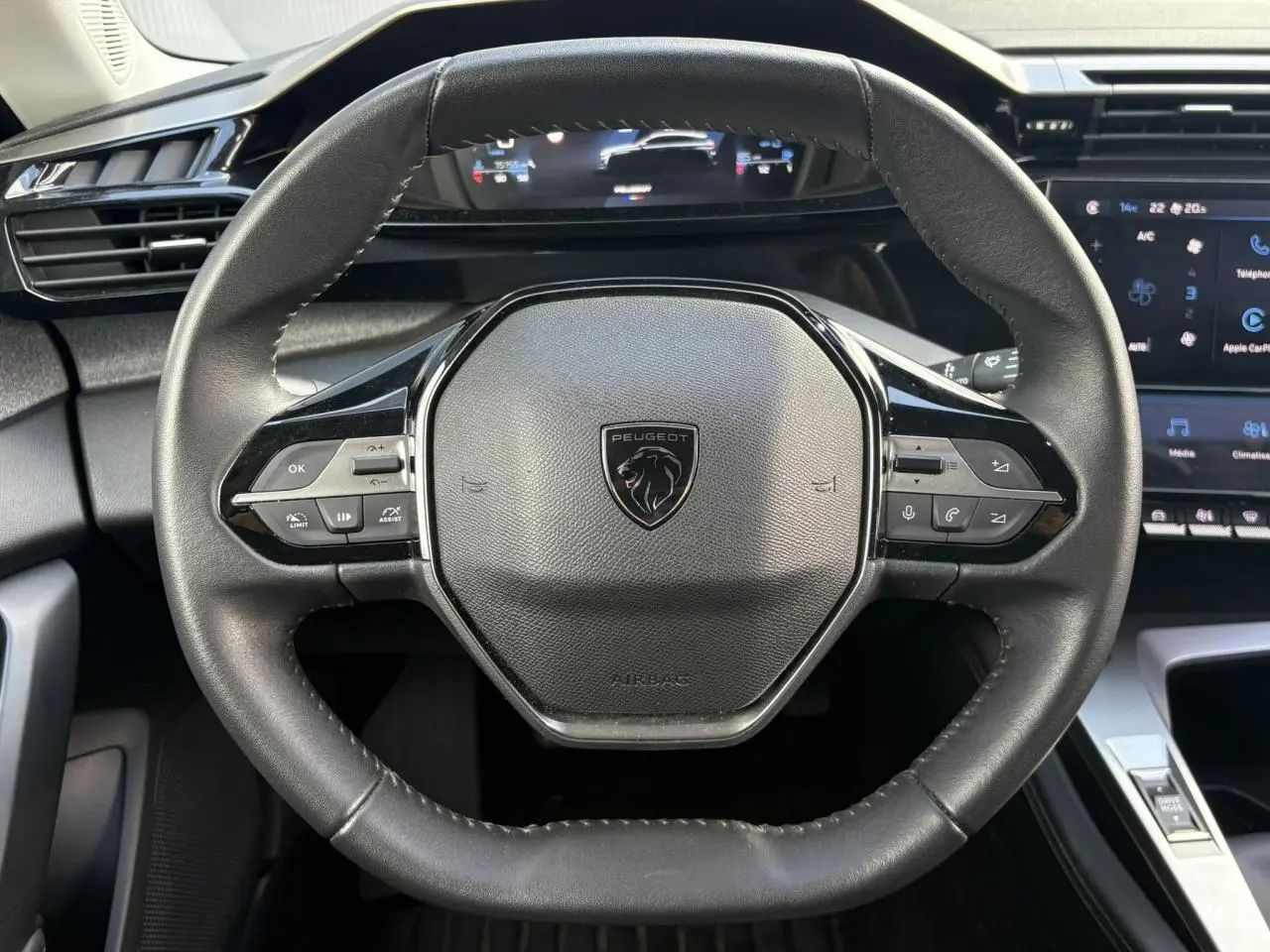 Vue rapprochée du volant cuir noir de la Peugeot 308 2024 avec commandes intégrées et tableau de bord numérique.
