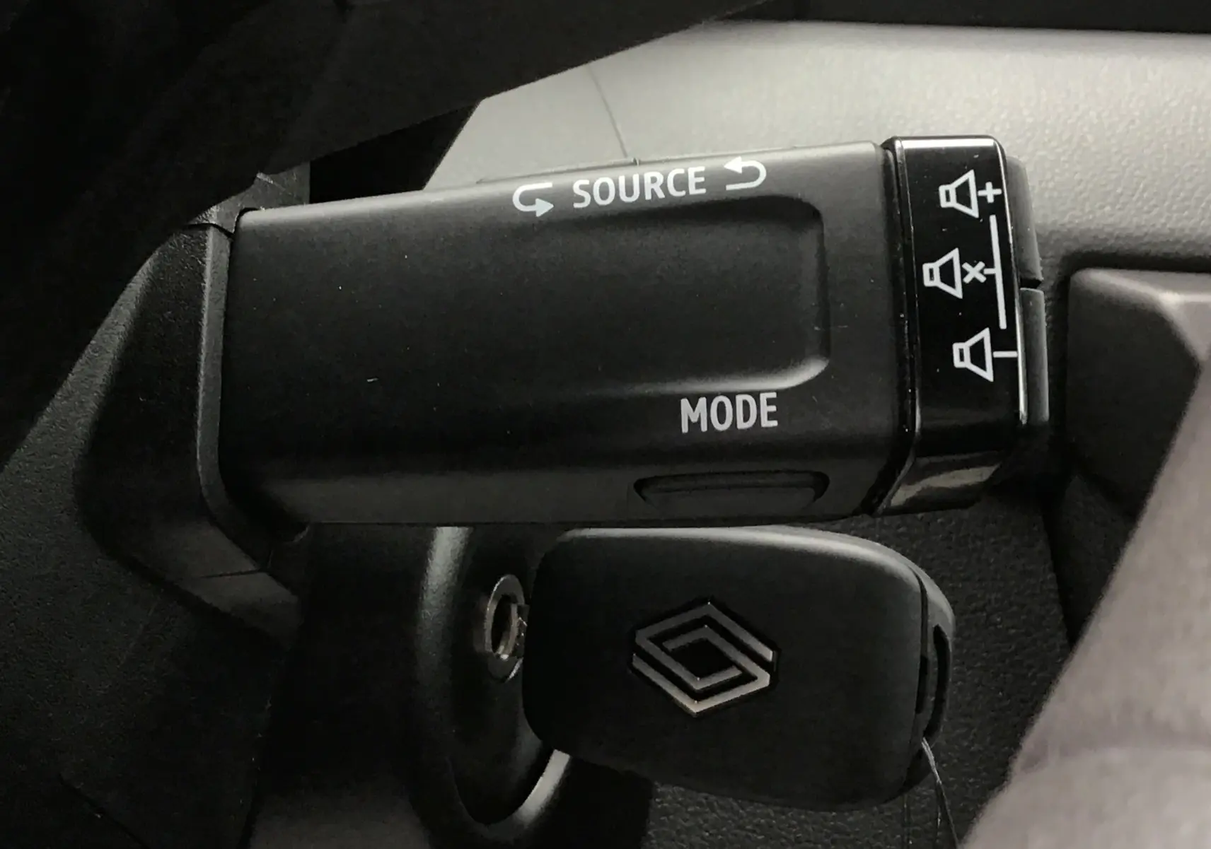 Gros plan sur la commande au volant et la clé avec logo Renault du Master blanc, version 2025, intérieur noir.