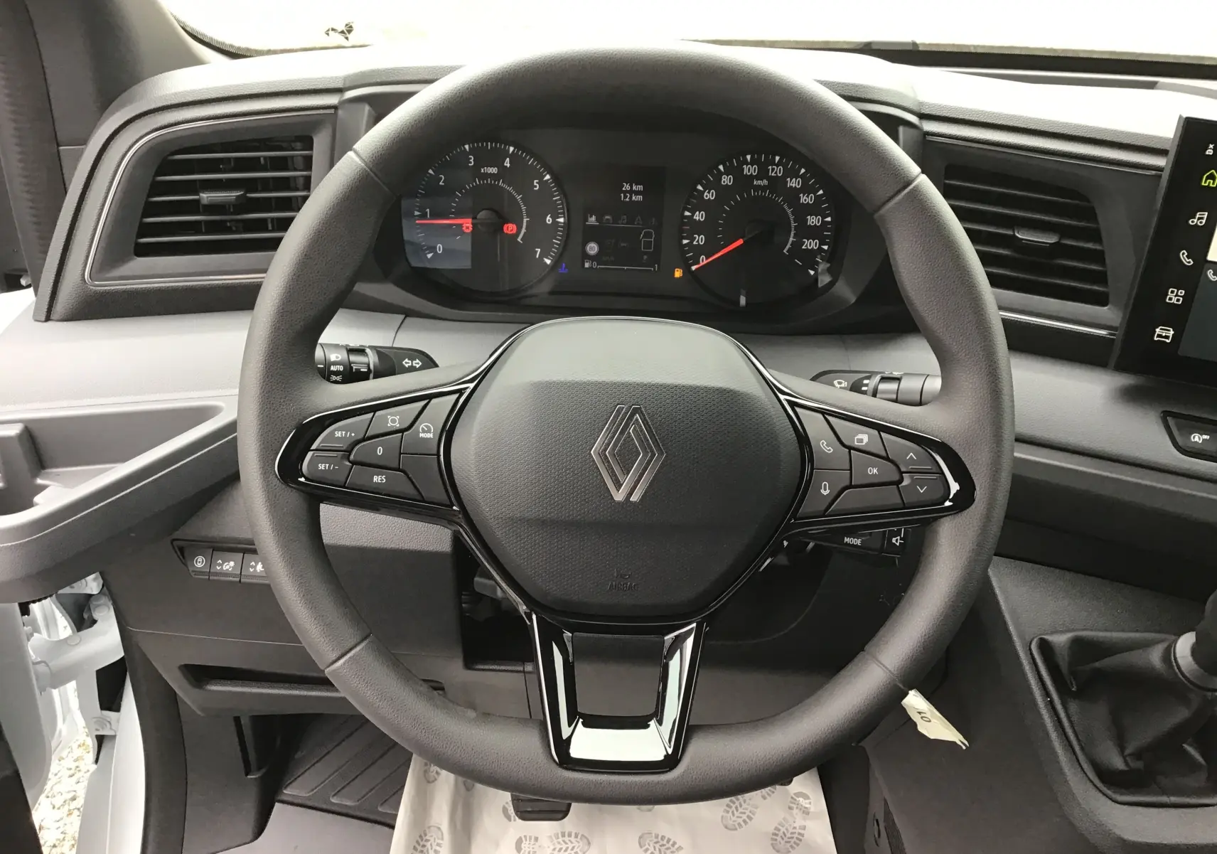 Vue frontale du volant noir et tableau de bord du Renault Master blanc avec commandes intégrées et écran tactile.