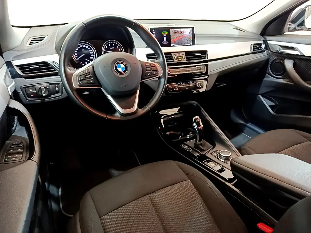 Vue intérieure avant droite du BMW X2 2023 avec tableau de bord noir, volant cuir multifonctions et écran central couleur.