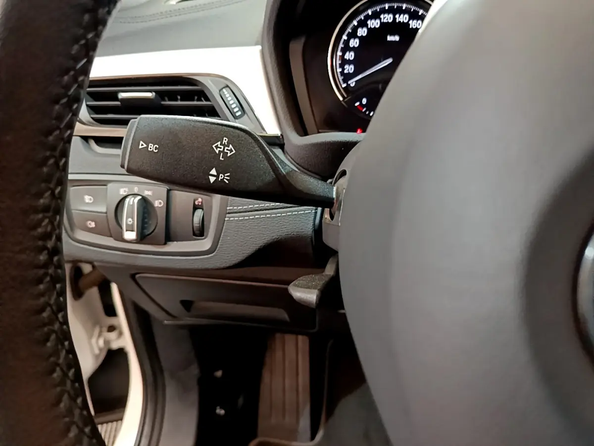 Gros plan sur la commande de clignotants à gauche du volant dans le tableau de bord noir du BMW X2 blanc 2023.