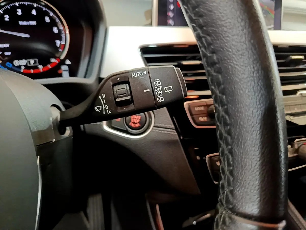 Gros plan sur la commande d’essuie-glace à gauche du volant cuir noir dans l’habitacle du BMW X2 blanc 2023.