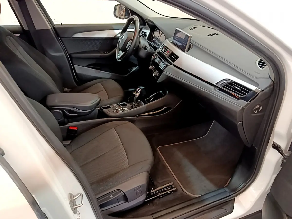 Intérieur noir du BMW X2 sDrive18i 2023 vu côté passager, avec tableau de bord moderne et écran central.