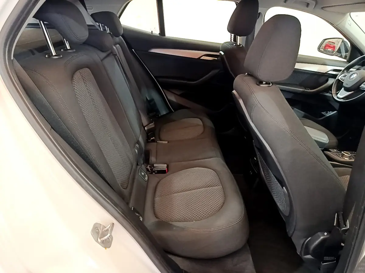 Intérieur de la BMW X2 blanc, vue latérale côté gauche sur la banquette arrière et le tableau de bord avant.