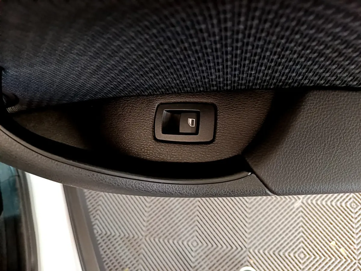 Bouton de commande de lève-vitre intégré dans la garniture intérieure côté gauche d'une BMW X2 blanche 2023.