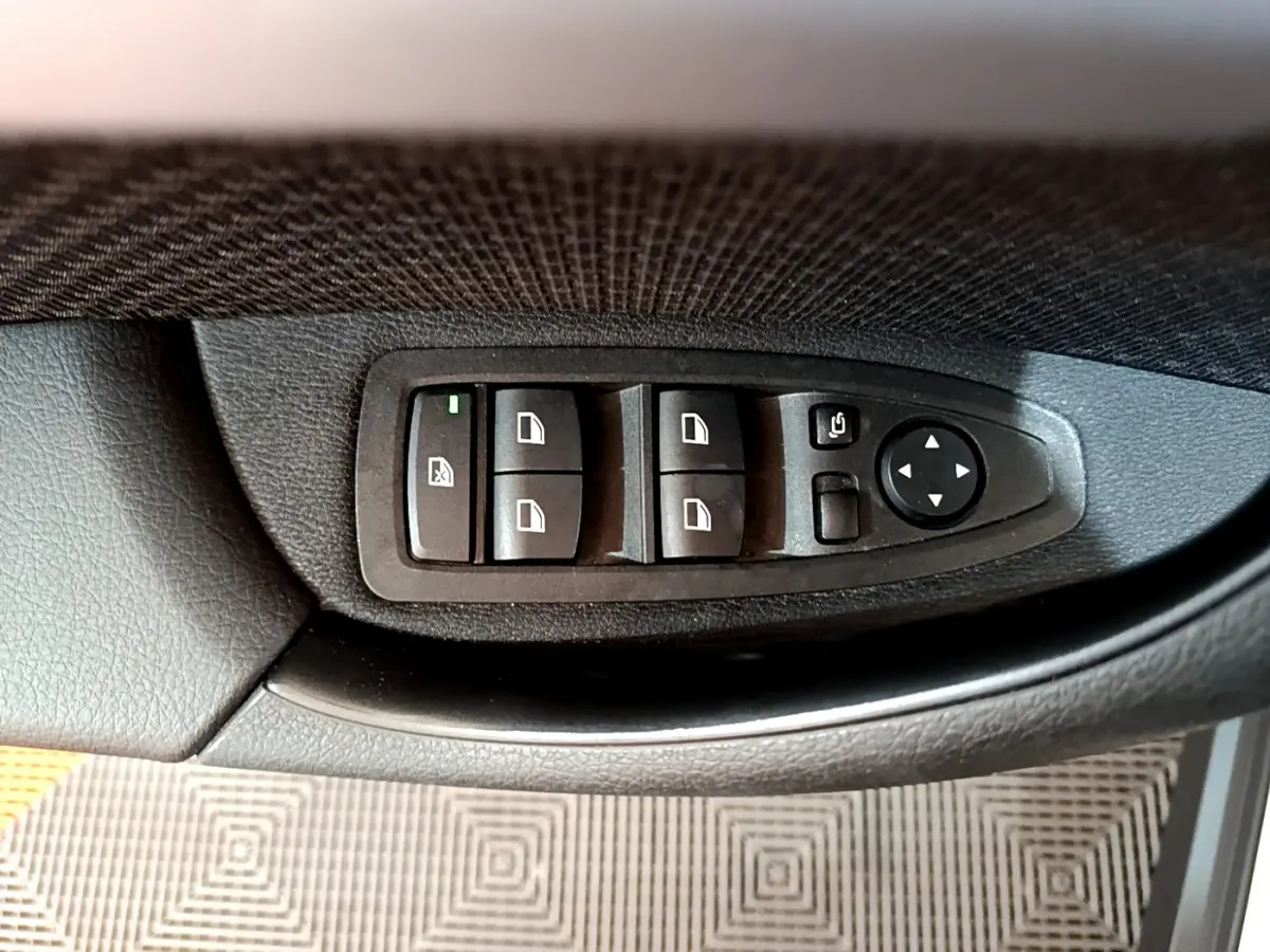 Panneau de commandes des vitres et rétroviseurs côté conducteur dans une BMW X2 blanc 2023.