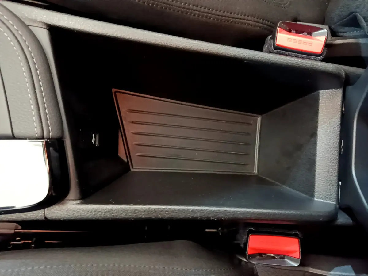 Vide-poche central noir avec ceintures de sécurité rouges dans l'habitacle d'une BMW X2 blanche 2023.