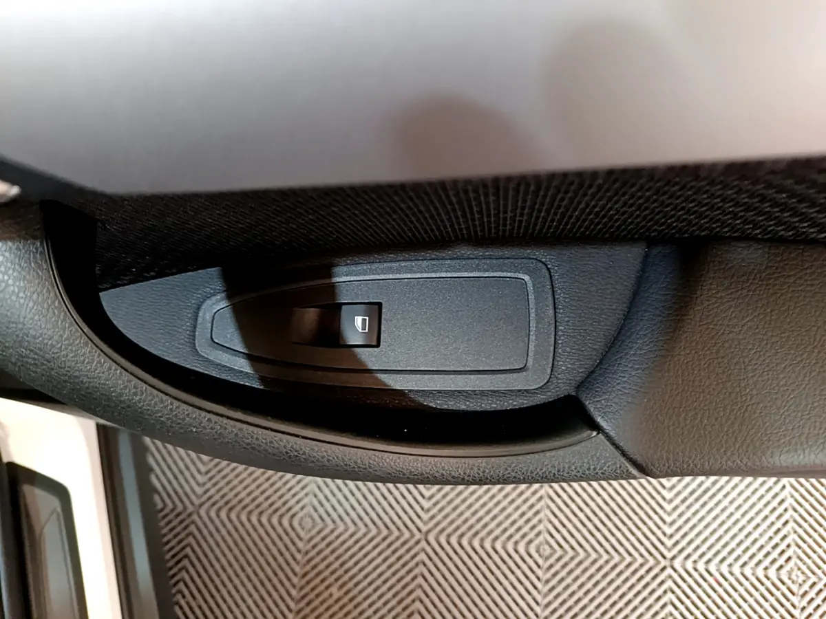 Bouton de commande de lève-vitre côté conducteur dans l'intérieur noir d'une BMW X2 blanc 2023.