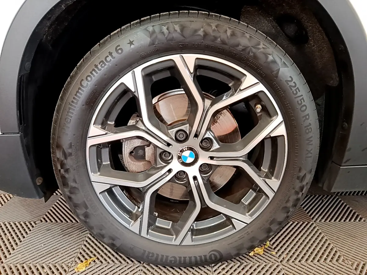 Gros plan sur la roue avant droite du BMW X2 blanc 2023, mettant en valeur la jante alliage et le logo BMW central.