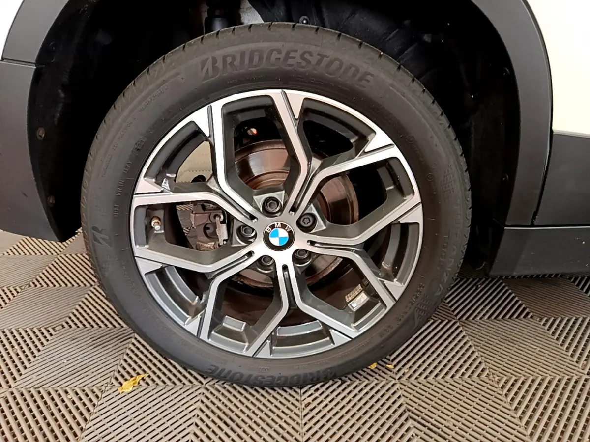 Gros plan sur la roue avant droite du BMW X2 blanc 2023, mettant en valeur la jante alliage et le pneu Bridgestone.
