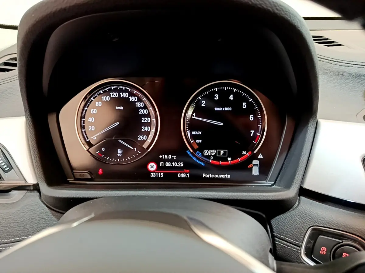 Tableau de bord numérique de BMW X2 blanc 2023, vue centrée sur les compteurs vitesse et régime moteur.